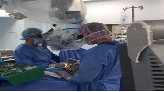 하늘색 모자를 쓴 A의사와 분홍색 모자를 쓴 L사 직원이 미세수술에 쓰이는 현미경을 함께 들여다 보고 있다.